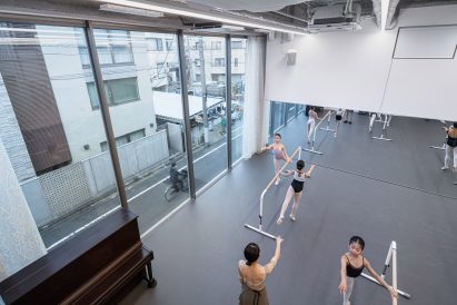 Interior of the ballet studio with dancers practising with a view overlooking the street