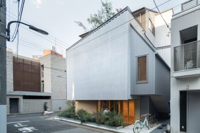 Rear view of Tokyo Ballet House showing planted borders, the ribbed facade and the upper residential volume set back above the street