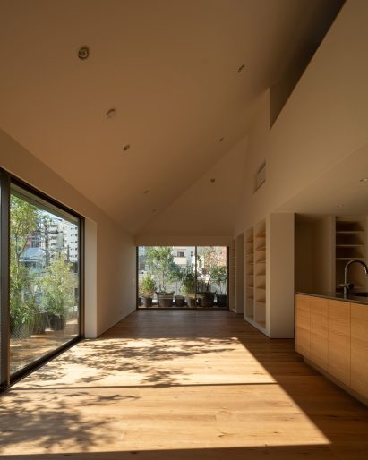 Sunlit living space with oak flooring leading to planted outdoor terraces through large sliding doors