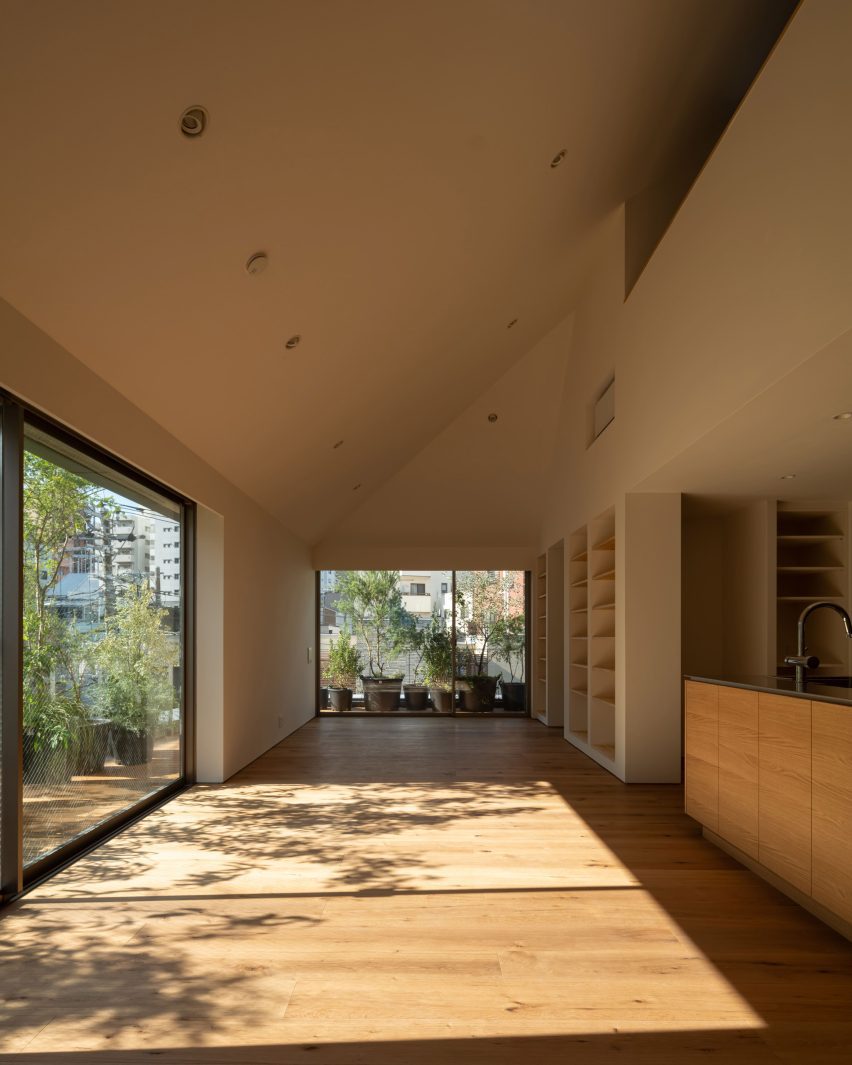 Sunlit living space with oak flooring leading to planted outdoor terraces through large sliding doors