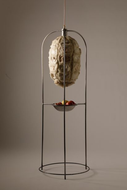 Photo of the Xero Cool bio-based fridge hanging suspended in its frame, showing a capsule made of organic-looking panels in roughly textured insulating biomaterials