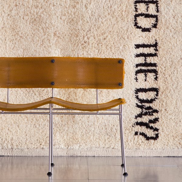 Photo of chair in front of textile wall hanging