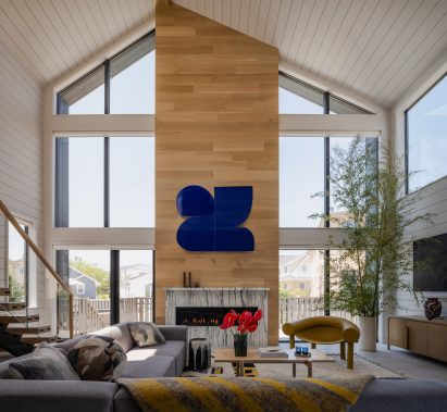 An oak-clad chimney stack sits between large windows in an airy family room