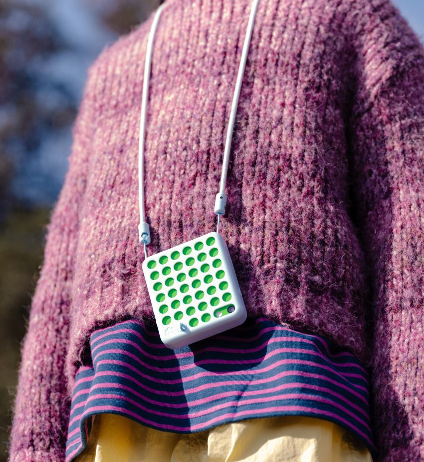 Close-up photo of the Freckle phone draped on a lanyard around the neck of a child wearing a fuzzy wool sweater in the outdoors