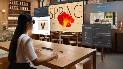 Image of a person from behind wearing the Meta VR Glasses as they work at a desk, with a virtual multi-screen set-up around her as if viewed through her eyes