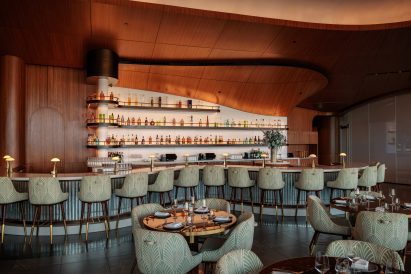 Shimmering tiles cover the front of a snaking bar, while the back bar is clad in illuminated Corian
