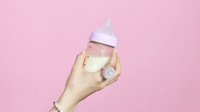 Hand with a wearable video game ring holding a baby bottle