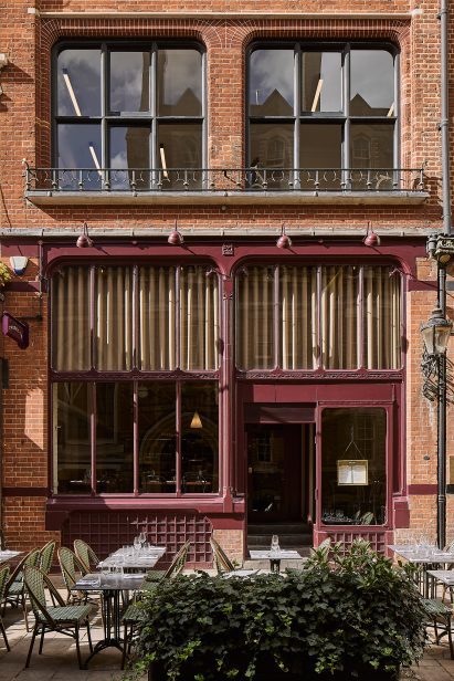 Photograph of the exterior of the restaurant, showing deep aubergine painted window panes and the terrace area.