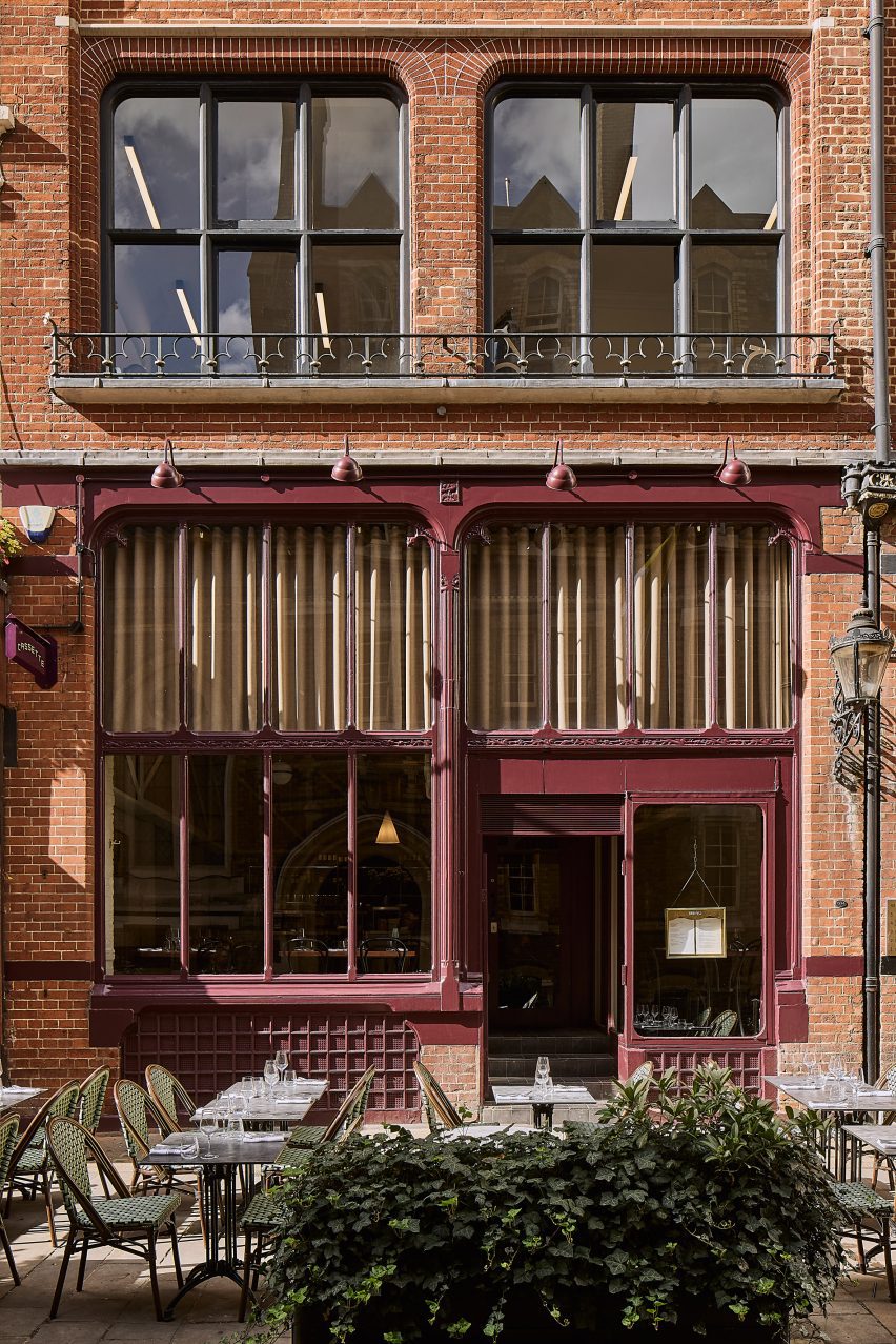 Photograph of the exterior of the restaurant, showing deep aubergine painted window panes and the terrace area.