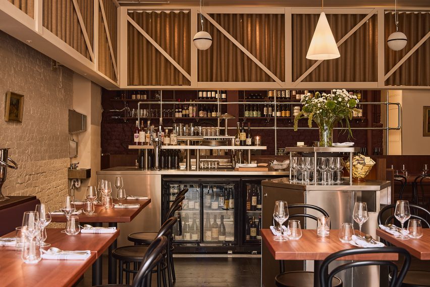 Photograph of a restaurant interior with wooden tables, a wrap-around curtain and stainless steel bar islands.
