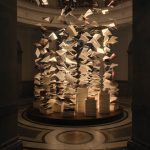 Suspended paper sheets and books forming an installation inside a grand museum interior