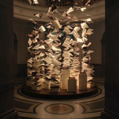 Suspended paper sheets and books forming an installation inside a grand museum interior