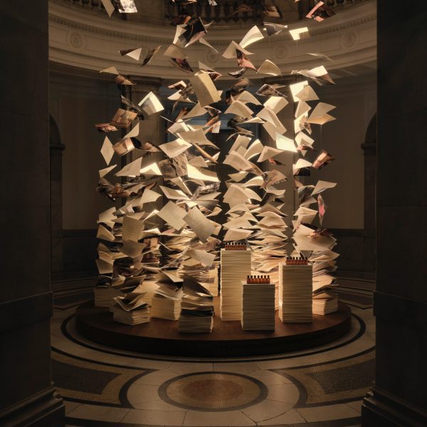 Suspended paper sheets and books forming an installation inside a grand museum interior