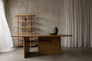 Large dining table in interior with concrete walls and floors and white curtains