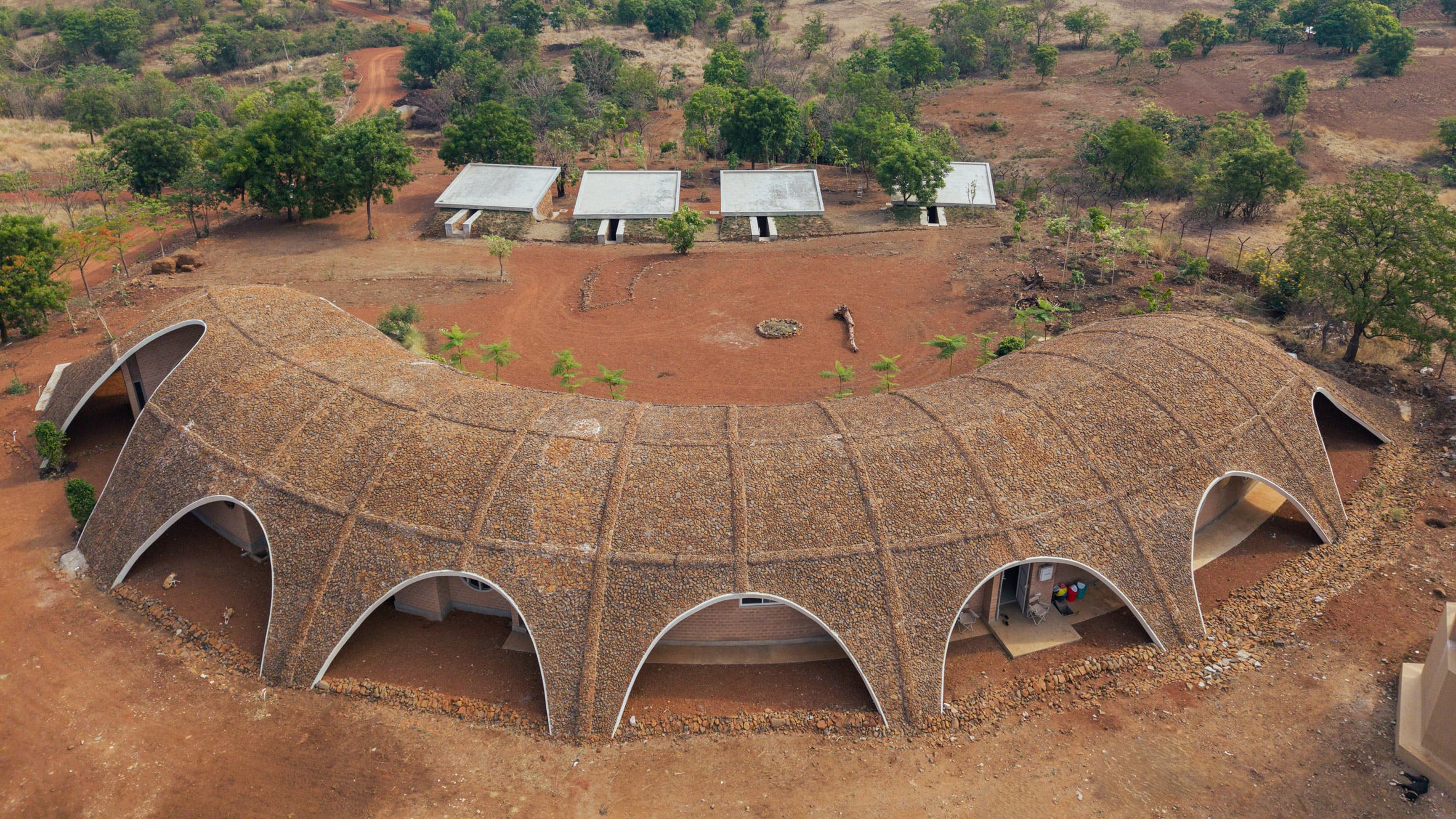 Stone-covered roof provides “absolute camouflage” for Gamaya Farms eco-resort in India