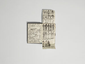 An open notebook containing handwritten notes and costume sketches